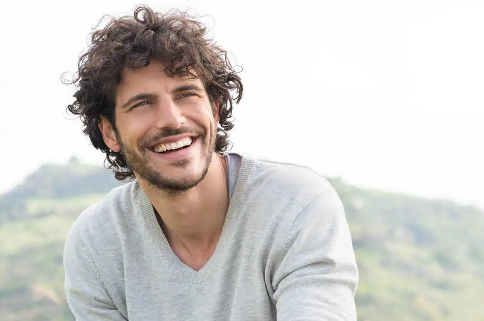 a man smiling with curly hair